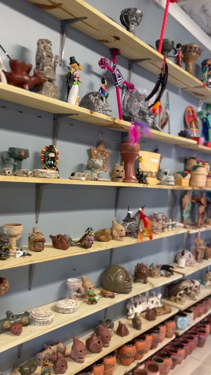 Repisas de la tienda Toknihuan con figuras de barro, sahumadores y arte plumario